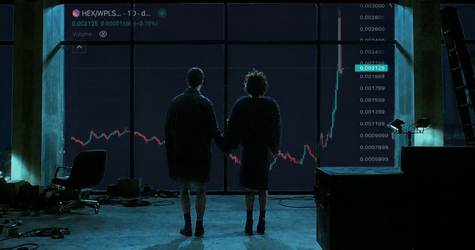 Two silhouetted figures holding hands stand before large screens showing cryptocurrency trading charts, including a HEX/WPLS pair with a candlestick graph and price values.