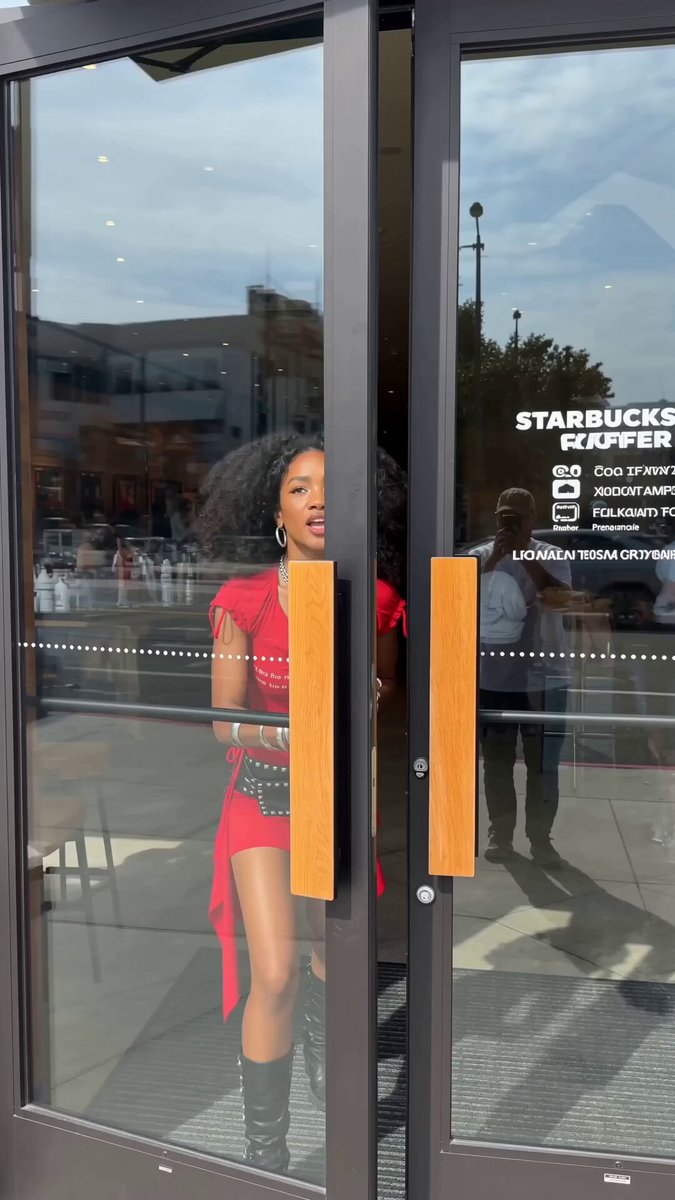 The image shows a woman standing outside of a Starbucks coffee shop, with her back facing the camera. She is wearing a red dress and black boots. There are two doors visible in the scene - one open door leading out from the left side of the photo, and another closed door on the right side. The post that reads "Just use Jupiter bb" appears to be related to the Starbucks coffee shop or possibly an advertisement for it.