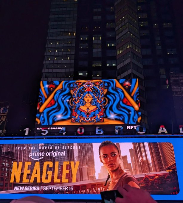 A vibrant digital artwork is displayed on a Times Square billboard above an advertisement for "NEAGLEY," a Prime Original series premiering September 16. The artist's NFT piece is being showcased at NFT NYC 2026, combining bright psychedelic imagery with the iconic NYC backdrop as noted in the caption.