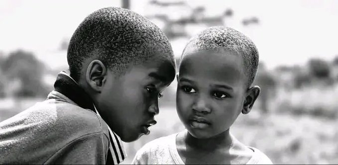 A black and white photograph showing two young boys standing close together, gazing thoughtfully in opposite directions.
