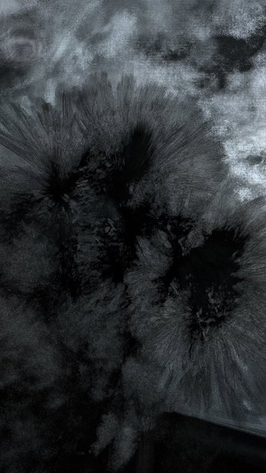 A dark, textured abstract image with black splattered or ink-burst patterns radiating outward against a greyish background, resembling ink dropped in water or burnt marks.