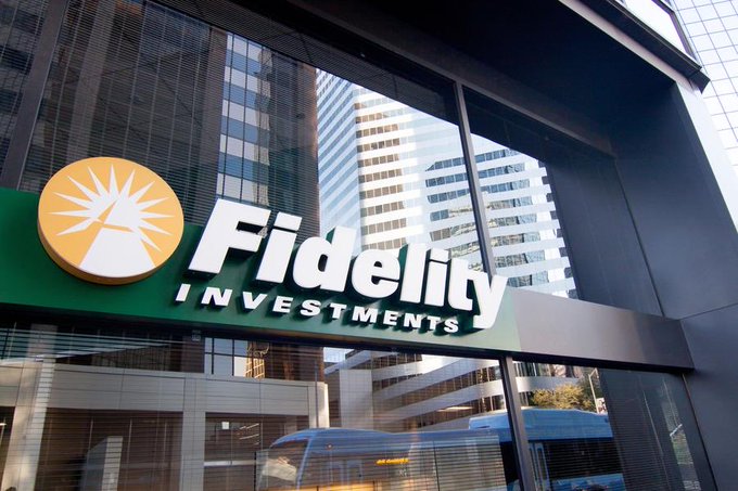 The Fidelity Investments sign sits prominently on a glass-fronted building in an urban setting, with reflections of surrounding skyscrapers visible in the windows. The image directly relates to the post, showcasing the brand of the $7 trillion asset manager announcing its plans to add $ETH staking and quarterly cash payouts to its spot Ethereum ETF.