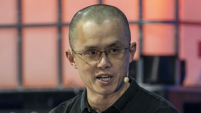 Changpeng Zhao (CZ), founder of Binance, is shown speaking at an event with a headset microphone, appearing to critique cryptocurrency platform Hyperliquid's lack of KYC requirements while referencing his own prison sentence tied to compliance failures. His serious expression and engaged posture underscore his warning about the risks of platforms allowing transactions without identity verification.