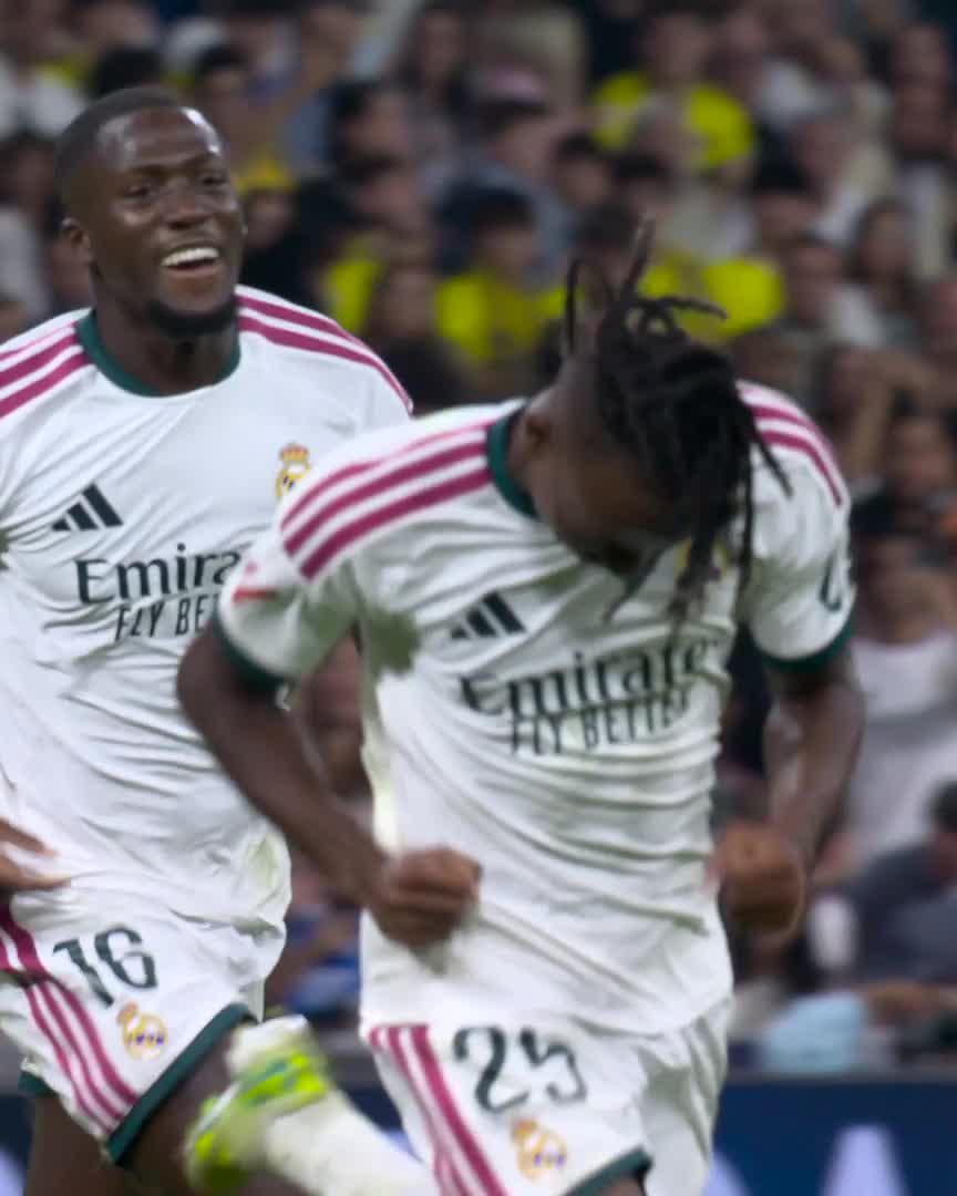Real Madrid players wearing white jerseys with "Emirates FLY BETTER" sponsor text celebrate, with player #25 visibly emotional with his head bowed and player #16 smiling joyfully behind him, capturing the moment Yan Diomande scored his first-ever goal for the club.