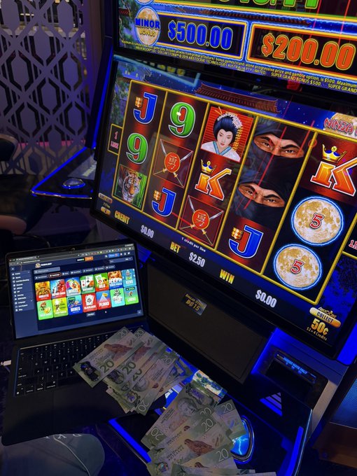 urn of gold coins sits on a desk, with a slot machine displaying a joker and a black screen showing the game's interface.