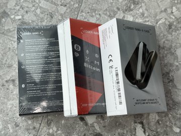 The image shows a sealed Ledger crypto hardware wallet box, side-by-side with its opened packaging revealing the "Nano X" device and Bitcoin branding inside. This relates to the post, where the user is debating whether to open or return their newly purchased Ledger from Token2049, still shrink-wrapped and visible on the left.