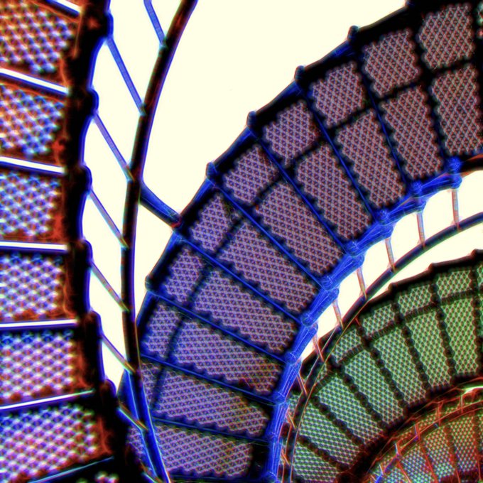 A close-up abstract image showing curved, grid-like textured surfaces in blue, green, and brown tones with a dotted pattern.