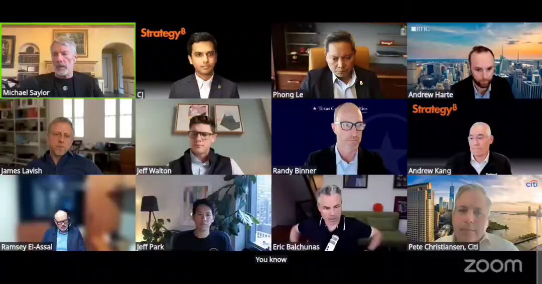 The image shows a group of people sitting around a table for a video conference call. There are at least 12 people visible in the screen, with each person's face clearly displayed. The participants appear to be engaged in a discussion or meeting related to Bitcoin. One man is wearing glasses and has a name tag on his shirt, while another man is holding a book. The group seems to be focused on the topic of Bitcoin and its potential uses for funding a dividend.