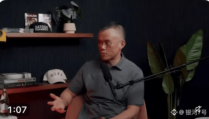 A man with glasses speaking into a microphone in a podcast/video setup, timestamped 1:07, with a 'Satoshi Nakamoto' book and Galaxy cap visible on the shelf.