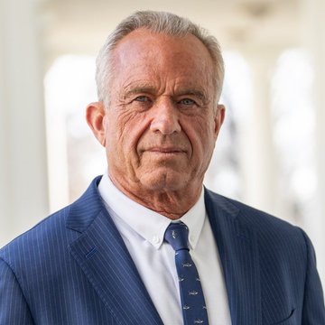 A professional headshot of an older man with gray hair, wearing a blue pinstripe suit and a patterned tie.