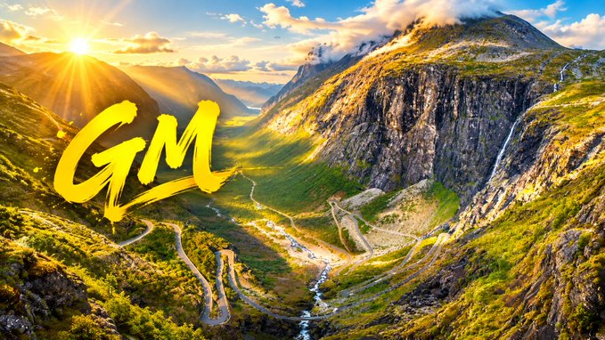 A vibrant landscape photograph of a green valley with a winding road and waterfall, featuring large yellow brush-stroke text 'GM' (Good Morning) overlaid on the image.