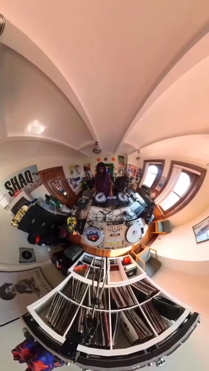 The image shows a room with a large circular window, which appears to be a part of a dome-shaped ceiling. In this room, there are several records displayed on shelves or racks, indicating that it might be a music studio or a storage area for musical equipment. The perspective of the photo is taken from within the room, looking out through the circular window towards the outside world.