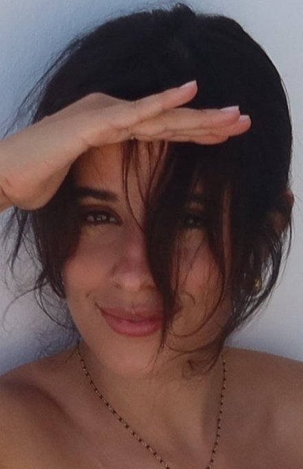 A woman with dark tousled hair shields her eyes from the sun with her hand while offering a subtle smile, paired with a motivational "Good Morning CT" post encouraging followers to stay focused on opportunities for the new week.