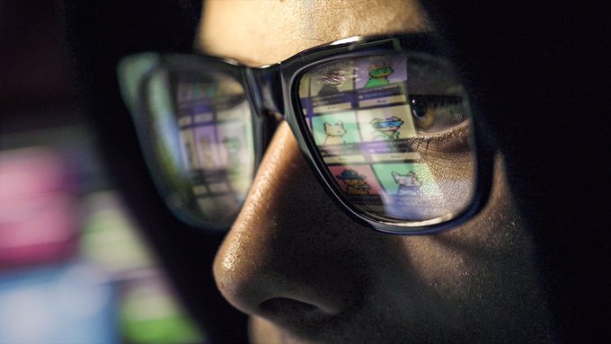 A close-up photograph of a person wearing glasses, with reflections of what appears to be the Cartoon Network website featuring various cartoon characters visible in the lenses.