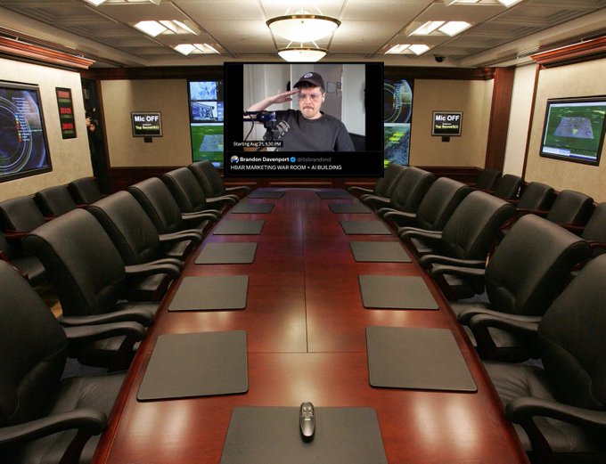 Conference room with a long wooden table surrounded by black chairs, featuring a large screen displaying Brandon Grossbart's podcast 'H2AR Marketing War Room.', with multiple monitor screens on the walls.