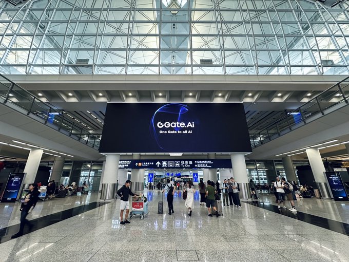 An airport terminal interior with a large digital billboard displaying 'oGate.AI - One Gate to all AI', with travelers and luggage visible in the concourse.