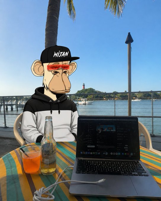 A Bored Ape NFT character wearing a 'MIJAN' cap and red sunglasses sits at a tropical outdoor table with a Coca-Cola bottle, an orange drink, and a laptop, overlooking a waterfront with a lighthouse.