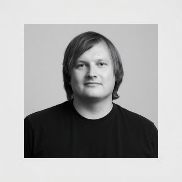 A black-and-white portrait of a man with shoulder-length hair wearing a black shirt, likely Stani Kulechov, founder of Aave, the DeFi platform mentioned in the post about deprecating 96 asset reserves and winding down six deployments.