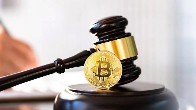 A physical Bitcoin coin standing upright next to a wooden judge's gavel resting on its sounding block, symbolizing cryptocurrency regulation and legal matters.
