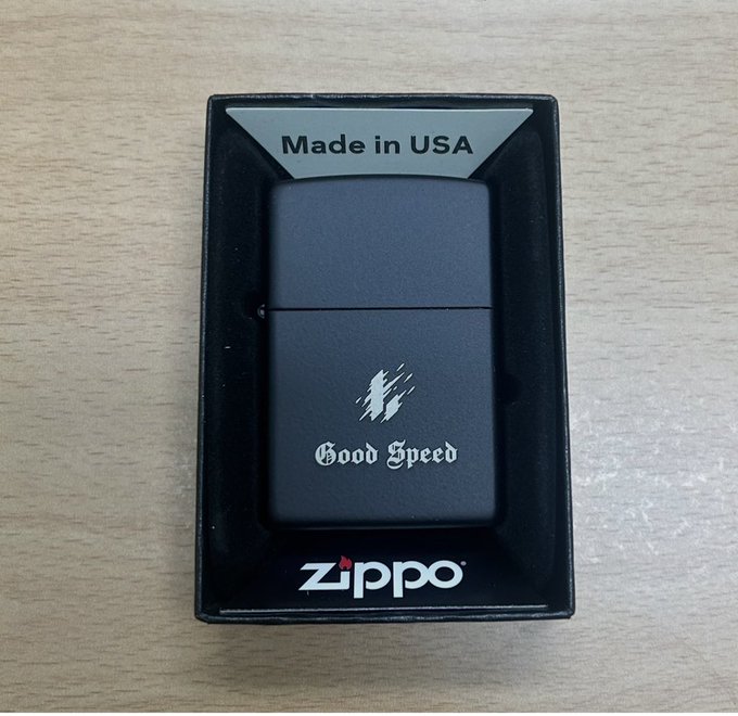 A matte black Zippo lighter engraved with 'Good Speed' rests in its box, labeled 'Made in USA'.