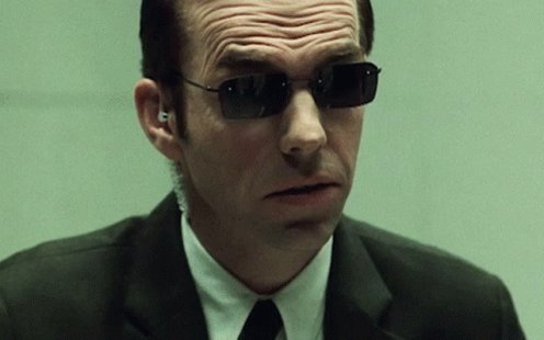 The image features a man wearing sunglasses, a suit, and a tie. He has a serious expression as he looks off into the distance. The caption "Gm Mr. Anderson" suggests that this could be a reference to the character Gm from the movie "The Matrix".