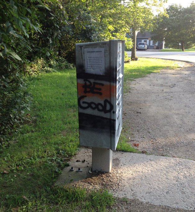 The image features a mailbox with graffiti on it, which says "be good" written in orange letters. The mailbox is located near a sidewalk and grassy area, possibly at an intersection or a street corner. In the background, there are trees that add some greenery to the scene. The post also mentions that the US dollar has been losing strength against other currencies, indicating a possible decline in the economy.