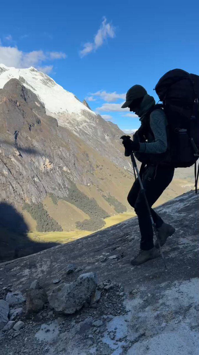 The image shows a person wearing hiking gear standing at the top of a mountain with their back facing the camera. The person has a backpack and appears to be taking a break or preparing for an adventure. The caption reads "Thank you to everyone at X that believed in this piece, and here on X that believed in me. Your support means more than I can properly put into words. When one ascent ends, another begins Cheers".
