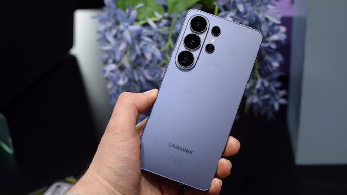A hand holds a lavender-colored Samsung Galaxy smartphone, displaying its rear camera array and "SAMSUNG" branding, set against a backdrop of blue flowers.

The image showcases a Samsung Galaxy device, visually reinforcing the post's claim about Samsung's dominance as the world's top smartphone maker, with 62 million Galaxy devices shipped in Q2 2026, now positioned as a platform for humanity-scale digital finance on Solana.