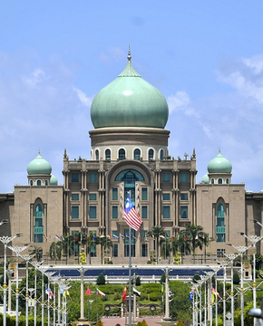 The image shows Malaysia’s Federal Court in Putrajaya, with its distinctive green domes and Malaysian flag. It accompanies the report that Malaysia will retain 322 Bitcoin seized from the 2015–16 Bitkingdom scam—worth about $27 million—while returning 176 Bitcoin to nine victims.