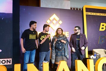 Four people stand on a stage holding awards in front of a 'BINANCE' branded backdrop.