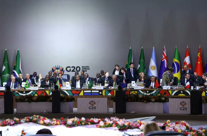 World leaders and finance officials are seated at a long table adorned with national flags during the G20 South Africa 2025 summit, where discussions focused on stablecoins and cross-border payments as key areas for crypto regulation.