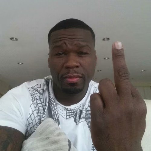 A close-up photo of the rapper 50 Cent wearing a white patterned shirt and raising his middle finger toward the camera.