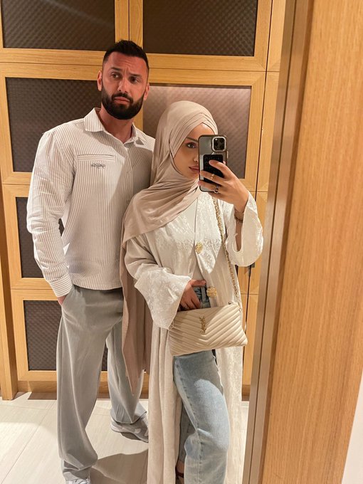 A couple poses for a mirror selfie, with the man wearing a striped button-up shirt and gray pants while the woman wears a beige hijab, embellished cream top, and carries a quilted crossbody bag, contributing to a "Day 3" series promoting $HYPE token growth.