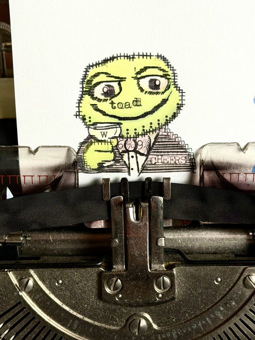 A whimsical ASCII art sticker featuring a green toad face with the word "toadi" being printed through a vintage typewriter.