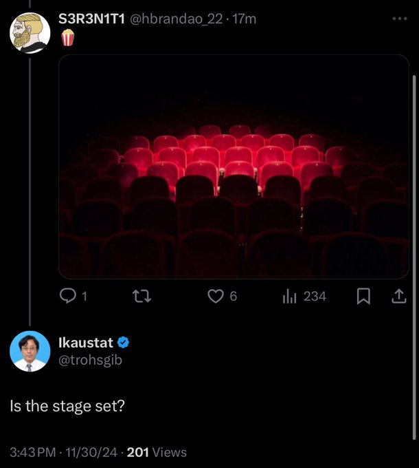 Screenshot of an X (Twitter) thread showing a tweet from @hbrandao_22 displaying an empty theater with red seats, replied to by verified user @trohsgib asking "Is the stage set?"