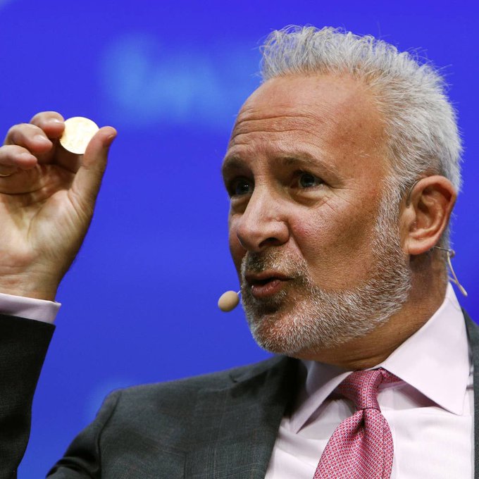 Economist Peter Schiff, a noted Bitcoin critic, holds up a coin while speaking at a conference, illustrating his long-standing skepticism toward cryptocurrency that aligns with his recent comments calling Bitcoin "worthless" following the failure of the CLARITY Act.