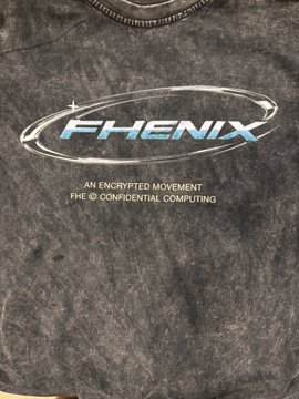 A dark grey t-shirt featuring a 'FHE' logo with the text 'FHENIX - AN ENCRYPTED MOVEMENT - FHE CONFIDENTIAL COMPUTING'.