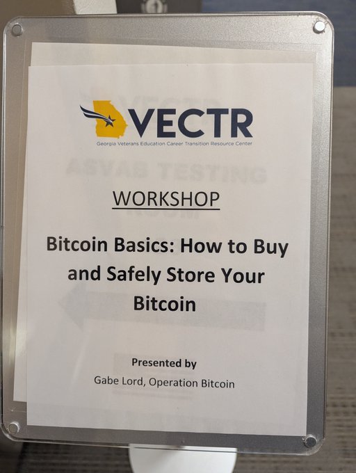 A workshop sign for VECTR (Georgia Veterans Education Career Transition Resource Center) advertises 'Bitcoin Basics: How to Buy and Safely Store Your Bitcoin', presented by Gabe Lord of Operation Bitcoin.