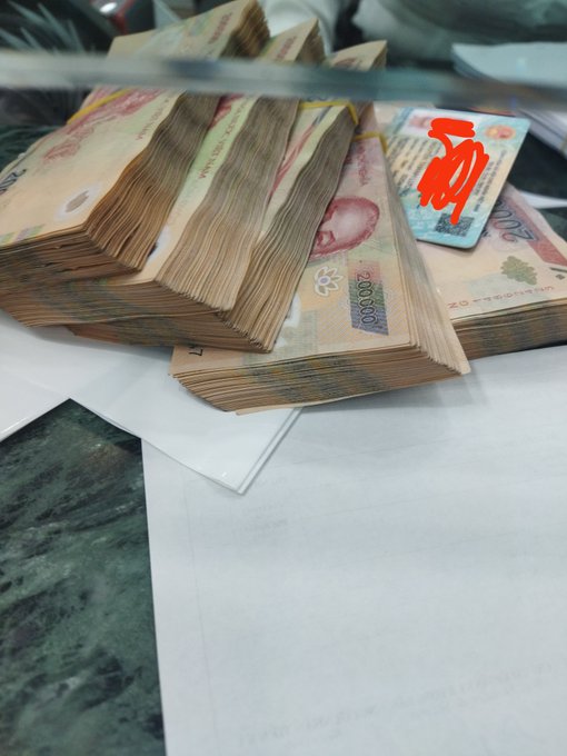 Stacks of Vietnamese Dong banknotes (200,000 VND denominations) piled on a counter next to a red card.