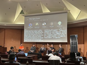 A panel of speakers sits at the front of an auditorium during "When Agents Think?" conference, with an audience watching.
