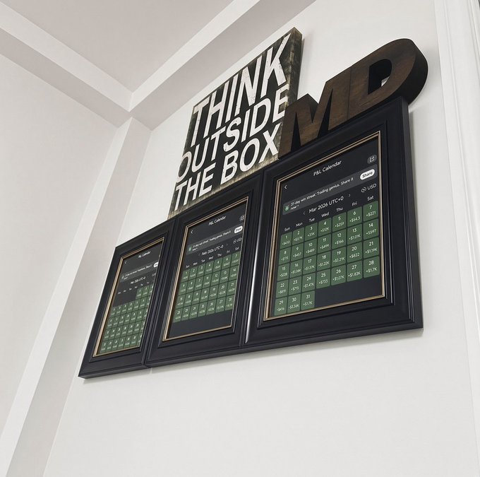 A wall-mounted display reads "THINK OUTSIDE THE BOX" in bold lettering above three framed screens showing financial trading calendars with green-tinted data grids, reflecting the post's message of hunger for success and market momentum from MD headquarters.