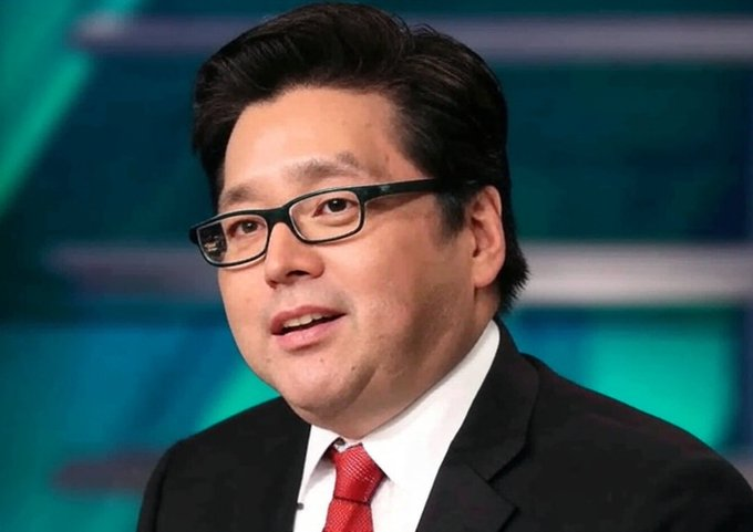 A photograph of an Asian man wearing glasses, a dark suit, and a red tie, appearing to be on a television news set.