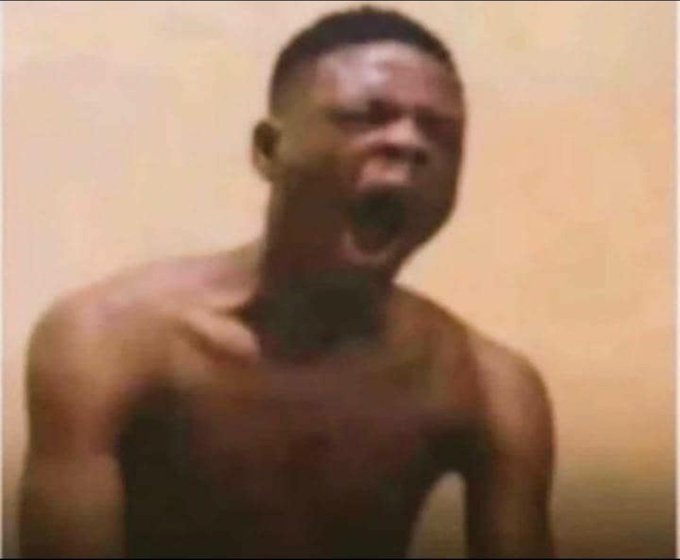 A blurry, grainy image of a shirtless man with his mouth wide open, appearing to yell or shout.
