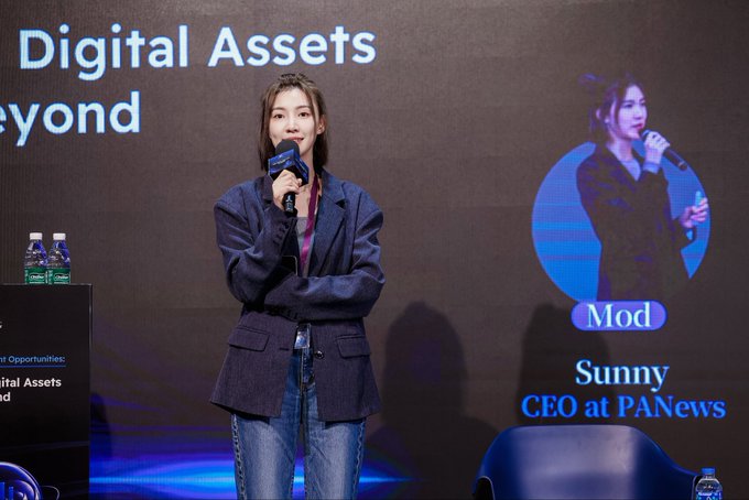 A photograph of a woman speaking on stage while holding a microphone, identified on the screen behind her as 'Sunny, CEO at PANews', during an event about 'Digital Assets Beyond'.