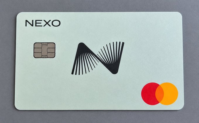 A Nexo Mastercard sits on a gray surface, featuring the company's name and stylized "N" logo, with its EMV chip and Mastercard's red and yellow circles visible. The image illustrates the post's review of the Nexo card, highlighting the smooth onboarding, Apple Pay functionality, and dual Debit/Credit modes mentioned in the review.