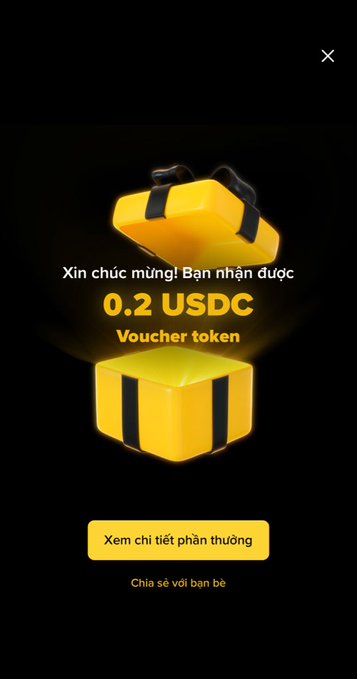 A Binance reward notification showing a glowing yellow gift box with the text 'Xin chúc mừng! Bạn nhận được 0.2 USDC Voucher token', with buttons to 'Xem chi tiết phần thưởng' and 'Chia sẻ với bạn bè'.