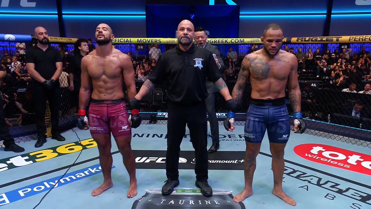 A UFC referee stands between two shirtless fighters in the octagon awaiting the judges' decision, with the fighter on the left wearing pink/red "UFC" shorts and the fighter on the right wearing blue "UFC" shorts with visible sponsor text including "bet365," "Polymarket," "toto wireless," and "DRAFTKINGS SPORTSBOOK" on the mat. The image captures the tense moment before a controversial decision that the poster is describing as a robbery, referencing Polymarket odds and the Verdict MMA scorecard.