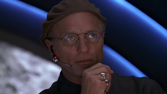 A man wearing a tan beanie, round glasses, and a headset microphone appears thoughtful, resting his hand near his chin. The image suggests a contemplative or skeptical reaction, fitting the post's request to copy-paste a ZEC breakout pattern for HYPE, implying the user is looking for a speculative trading comparison rather than a serious financial analysis.