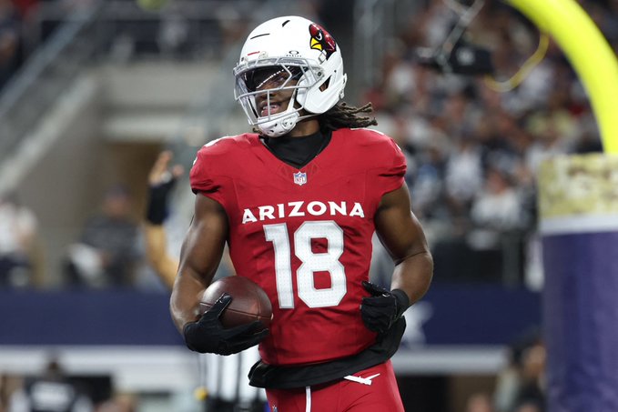 An Arizona Cardinals football player wearing jersey number 18 holds a football during a game.