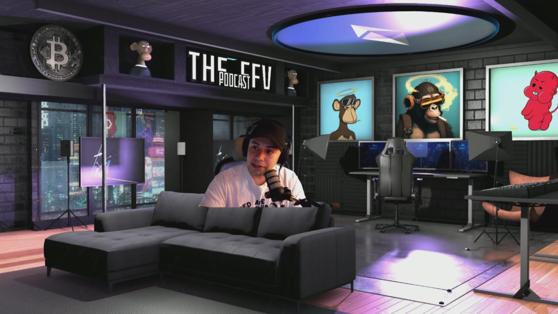 The image shows a man sitting on a couch with headphones on his head, possibly playing video games or listening to music. The room has a dark color scheme, giving it an edgy atmosphere. There are two computer monitors placed above the couch, indicating that this space could be used for both relaxation and work purposes. A chair is also present in the room, suggesting additional seating options.